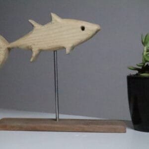Minimalist white ash wood fish sculpture mounted on stainless steel rod with wooden base, accompanied by a small succulent pot in a modern decor setting. Hand-carved eco-friendly wooden fish figurine displayed on tabletop with indoor plant, ideal for rustic and nature-themed interior styling. Artisan-crafted fish sculpture made of premium white ash wood, designed with clean lines and earthy accents for shelf or desk decor.